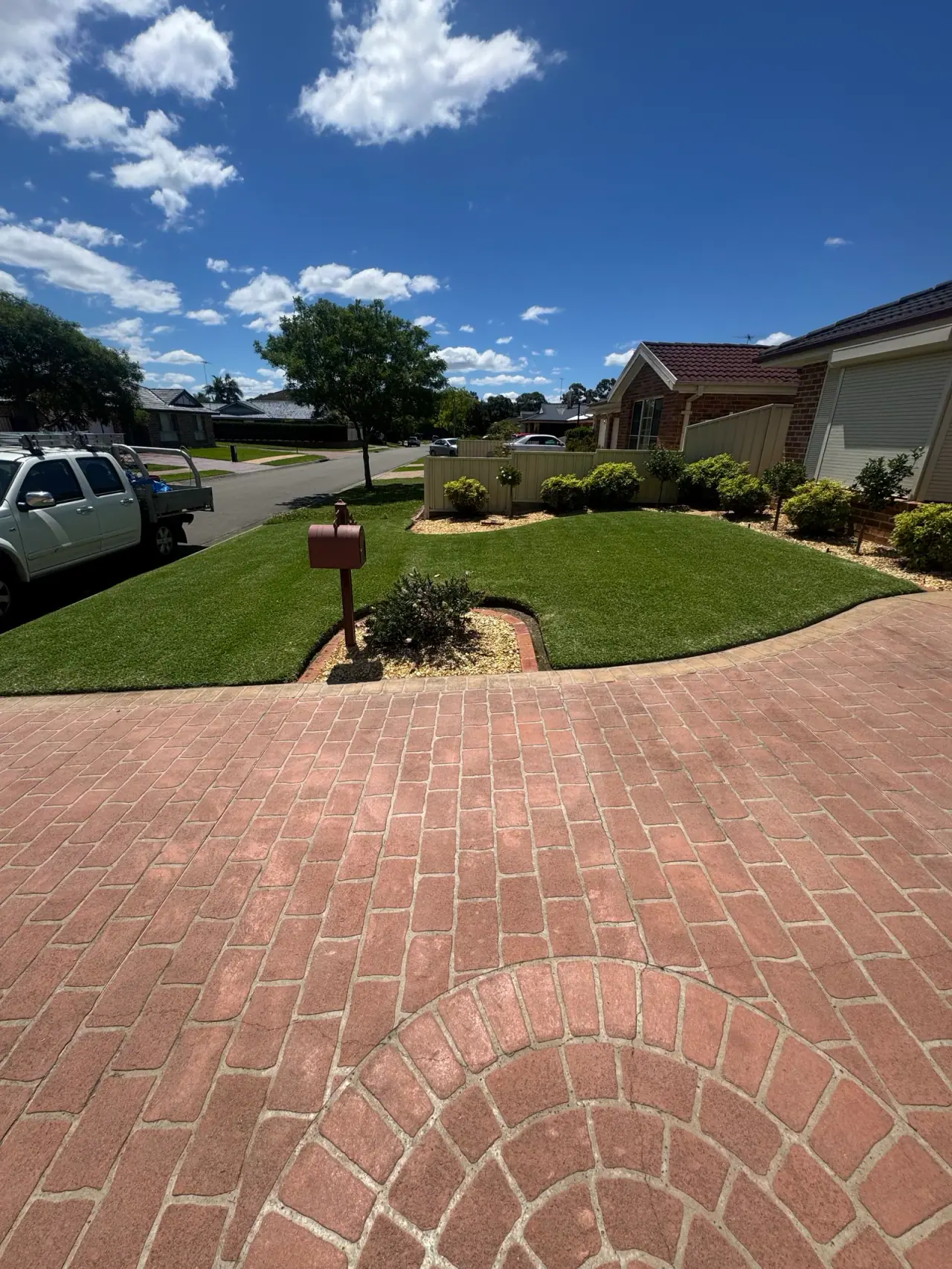 Mown lawn and garden presentation alongside a patterned driveway